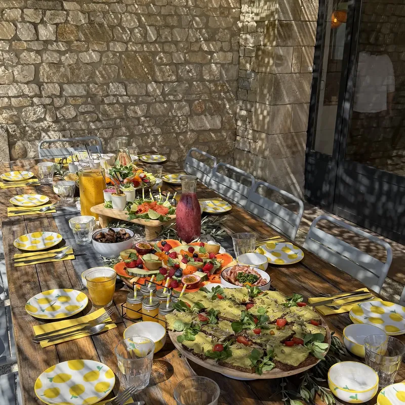 Buffet de salades et plats colorés sur une longue table dressée devant un mur en pierre