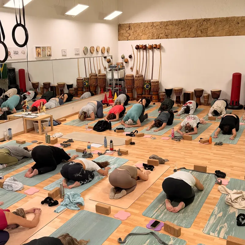 Élèves en posture de l’enfant sur des tapis dans une salle de yoga au parquet clair