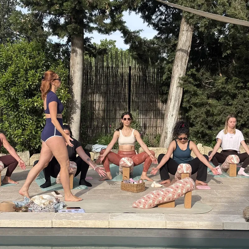 Professeure marchant entre les élèves assis sur leurs tapis au bord d’une piscine