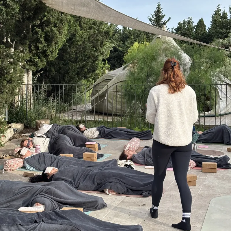 Relaxation finale en plein air : élèves allongés sous des couvertures, professeure debout au milieu