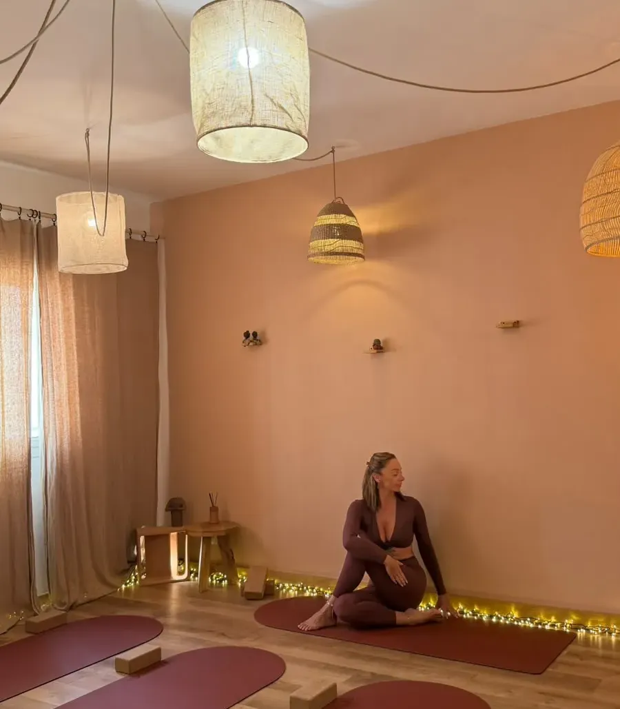 Charlotte, professeure de yoga, en posture de torsion assise sur un tapis de yoga dans le studio Yogalpilles à Salon-de-Provence